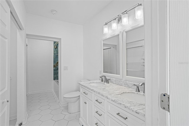 bathroom featuring toilet, double sink vanity, and tile patterned flooring