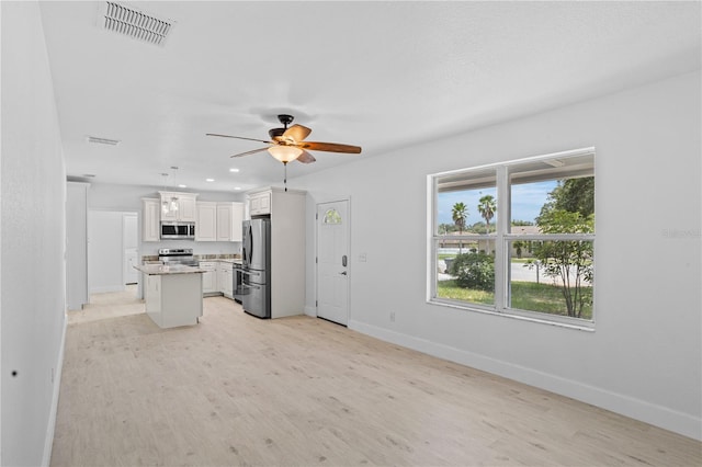 kitchen featuring ceiling fan, stainless steel appliances, a kitchen island, light hardwood / wood-style floors, and a wealth of natural light