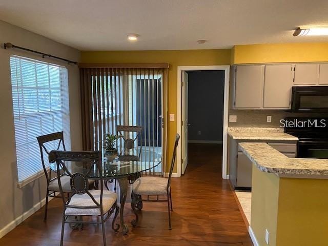 dining space featuring dark wood finished floors and baseboards