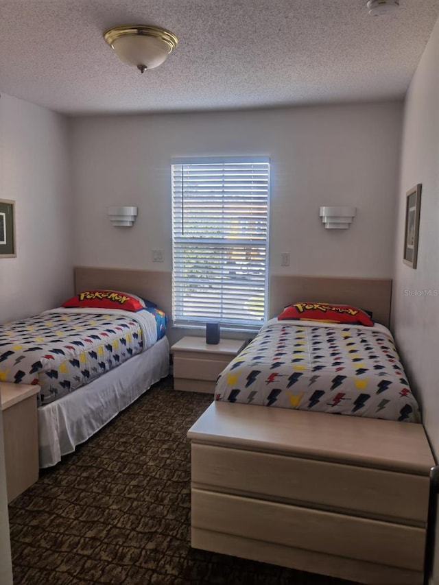 bedroom with dark carpet and a textured ceiling