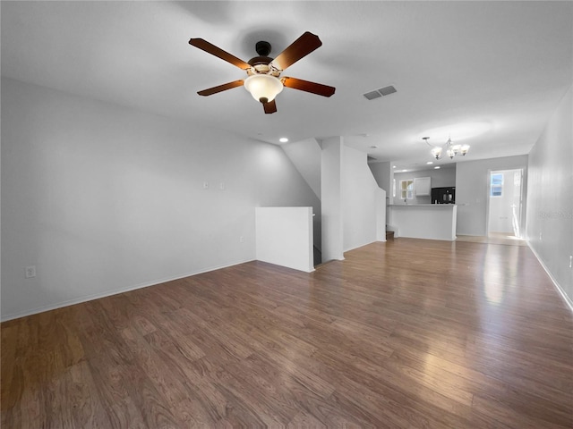 unfurnished living room with dark wood-type flooring and ceiling fan with notable chandelier