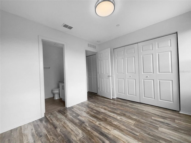 unfurnished bedroom featuring connected bathroom, a closet, and dark hardwood / wood-style floors