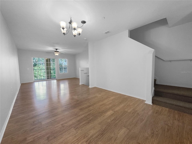 unfurnished living room with ceiling fan with notable chandelier and hardwood / wood-style floors