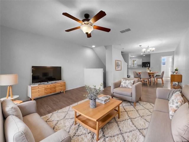 living room featuring ceiling fan with notable chandelier and light wood-type flooring