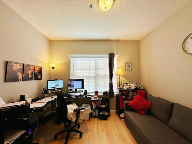 office area with light hardwood / wood-style flooring and a textured ceiling