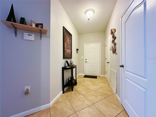 entryway with a textured ceiling and light tile patterned flooring