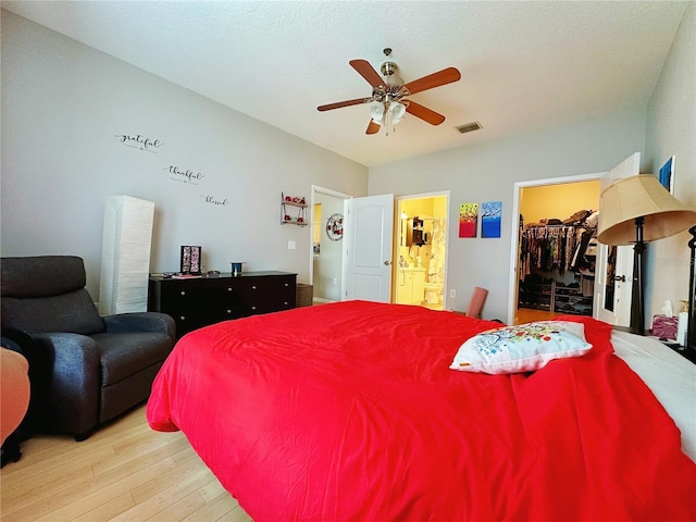 bedroom featuring ensuite bath, a spacious closet, a closet, ceiling fan, and light hardwood / wood-style floors