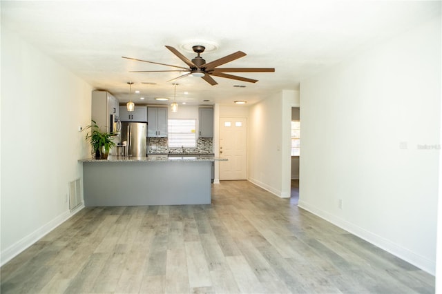 kitchen with stainless steel refrigerator, tasteful backsplash, light hardwood / wood-style flooring, kitchen peninsula, and gray cabinets