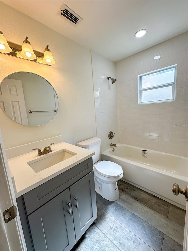 full bathroom with vanity, hardwood / wood-style flooring, toilet, and tiled shower / bath