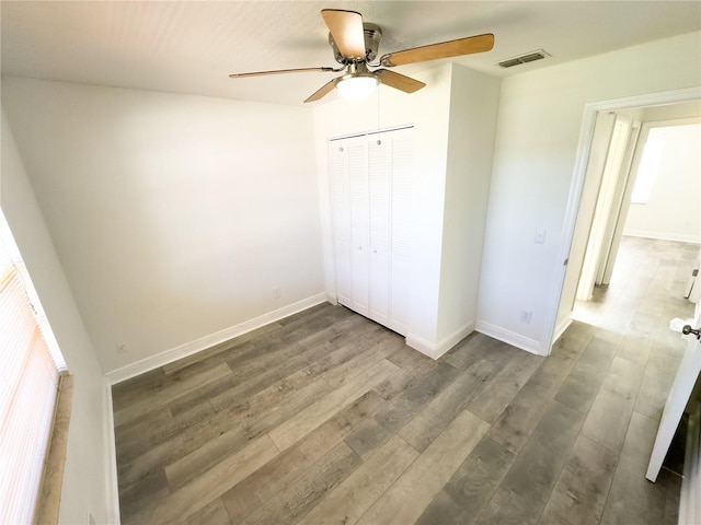 unfurnished bedroom with dark hardwood / wood-style flooring, a closet, and ceiling fan