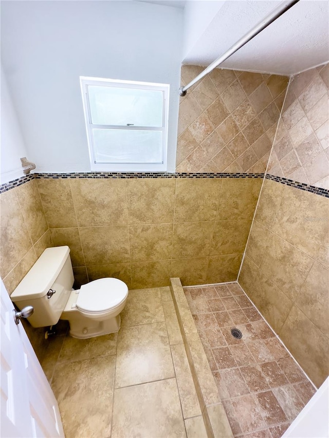 bathroom featuring tiled shower, toilet, and tile walls