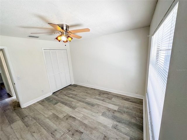 unfurnished bedroom featuring ceiling fan, light wood-type flooring, a textured ceiling, and a closet