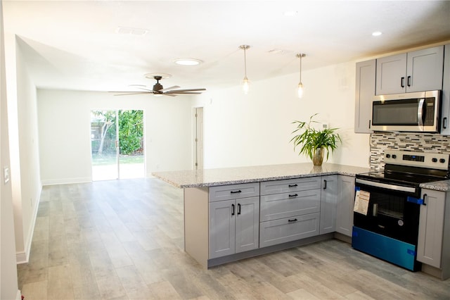 kitchen featuring gray cabinetry, stainless steel appliances, light stone counters, light hardwood / wood-style floors, and decorative light fixtures