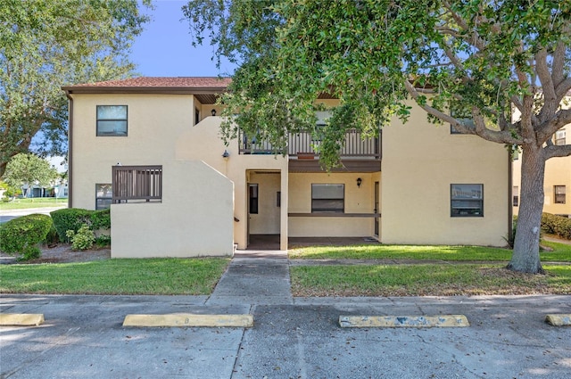 view of front facade with a balcony and a front lawn