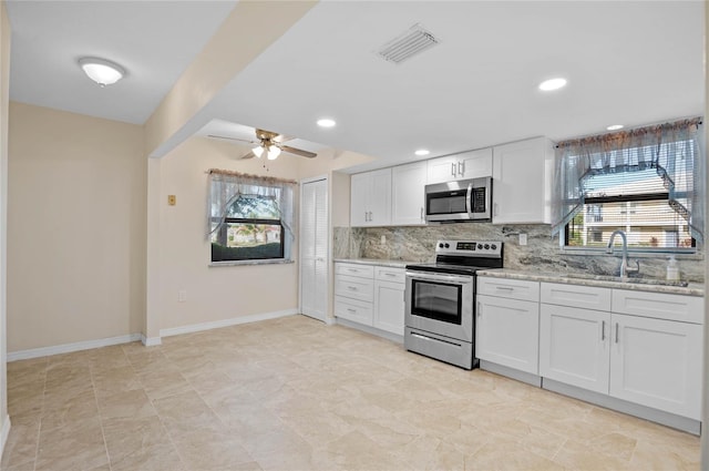 kitchen with appliances with stainless steel finishes, white cabinets, sink, light tile patterned floors, and ceiling fan