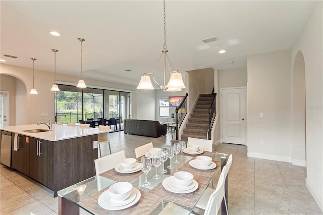 dining space featuring light tile patterned floors, a chandelier, and sink