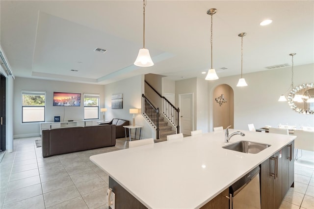 kitchen featuring a kitchen island with sink, dishwasher, a raised ceiling, and sink