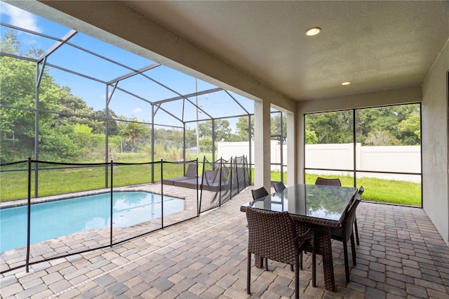 view of pool with a lawn, glass enclosure, and a patio