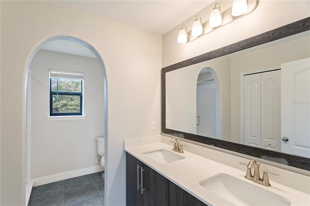 bathroom featuring toilet, vanity, tile patterned flooring, and a textured ceiling