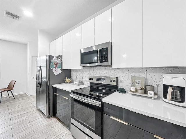 kitchen with backsplash, white cabinets, and appliances with stainless steel finishes