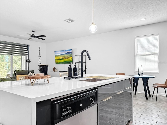 kitchen with pendant lighting, a textured ceiling, sink, ceiling fan, and stainless steel dishwasher