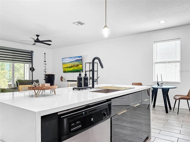 kitchen with sink, a textured ceiling, stainless steel dishwasher, pendant lighting, and ceiling fan