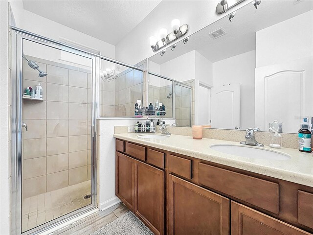 bathroom with vanity, a shower with door, and a textured ceiling