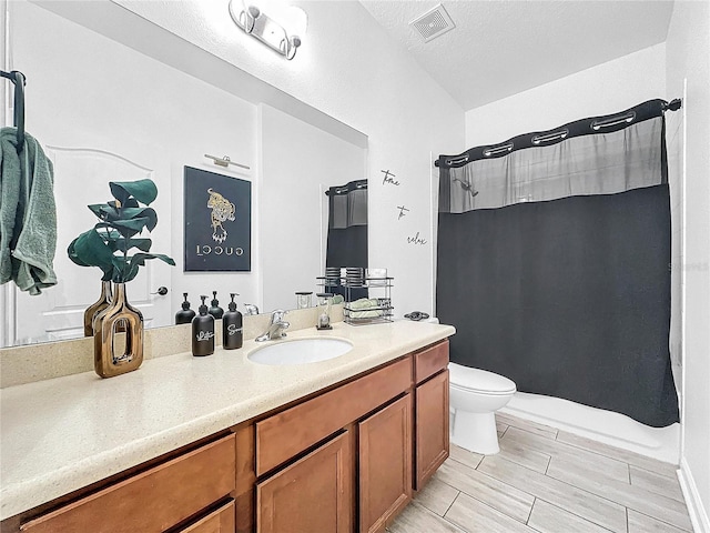 bathroom with a shower with curtain, vanity, toilet, and a textured ceiling