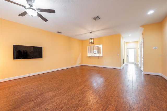 unfurnished room with a textured ceiling, ceiling fan with notable chandelier, and hardwood / wood-style flooring