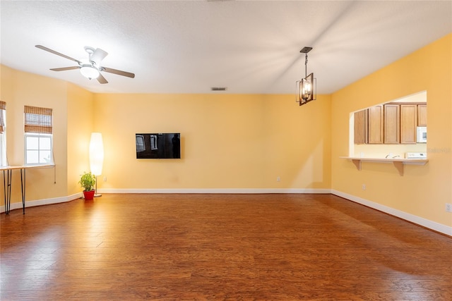 empty room with dark wood-type flooring and ceiling fan with notable chandelier