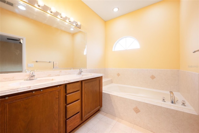 bathroom featuring tile patterned floors, a relaxing tiled tub, and vanity