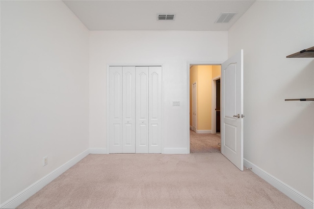 unfurnished bedroom featuring light carpet and a closet