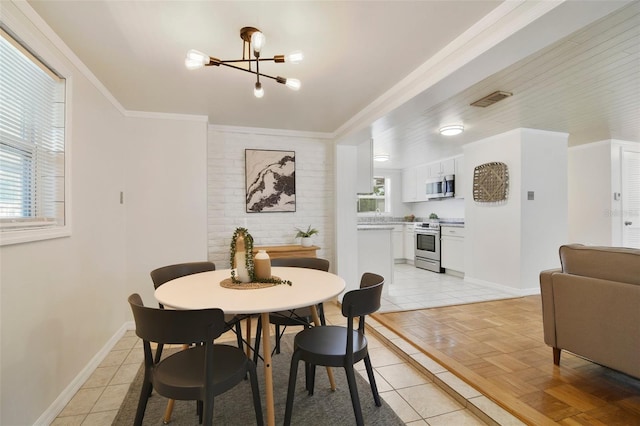 dining space with light parquet floors, a notable chandelier, and ornamental molding