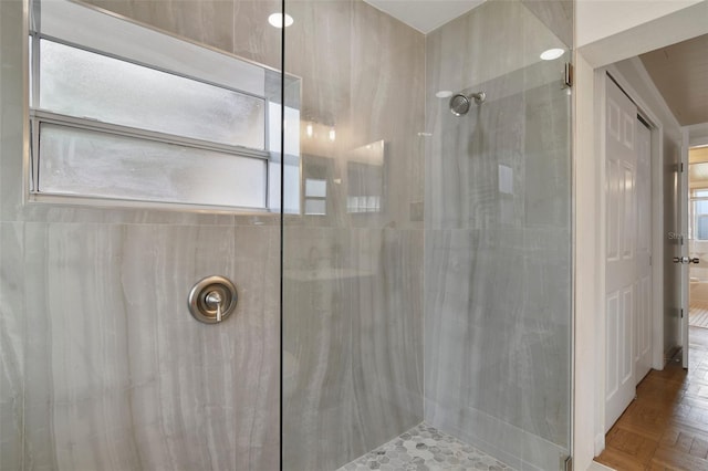 bathroom featuring tiled shower, parquet floors, and a wealth of natural light