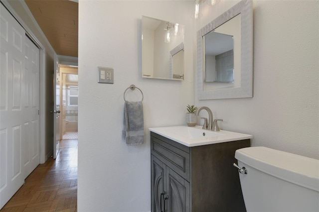 bathroom featuring vanity, parquet floors, and toilet