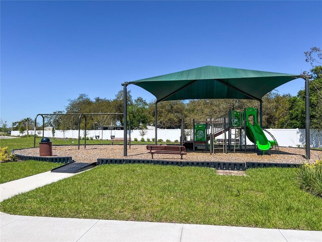 community play area featuring a yard and fence