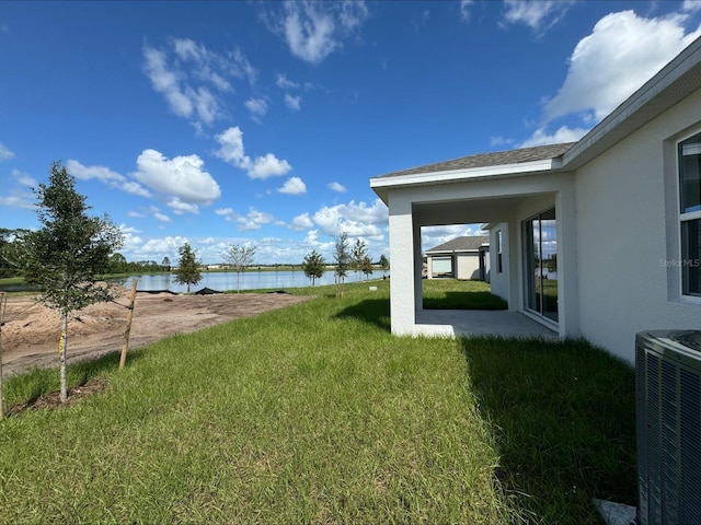 view of yard with a water view, central air condition unit, and a patio