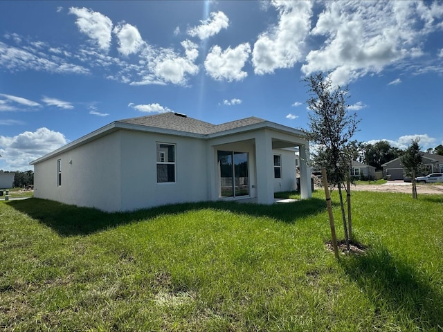 back of property featuring a yard, a shingled roof, and stucco siding