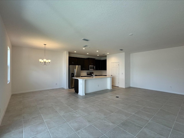 kitchen with stainless steel appliances, light countertops, open floor plan, an island with sink, and a chandelier