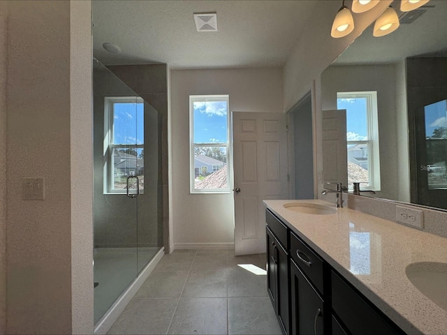 bathroom with double vanity, visible vents, tile patterned flooring, a shower stall, and a sink