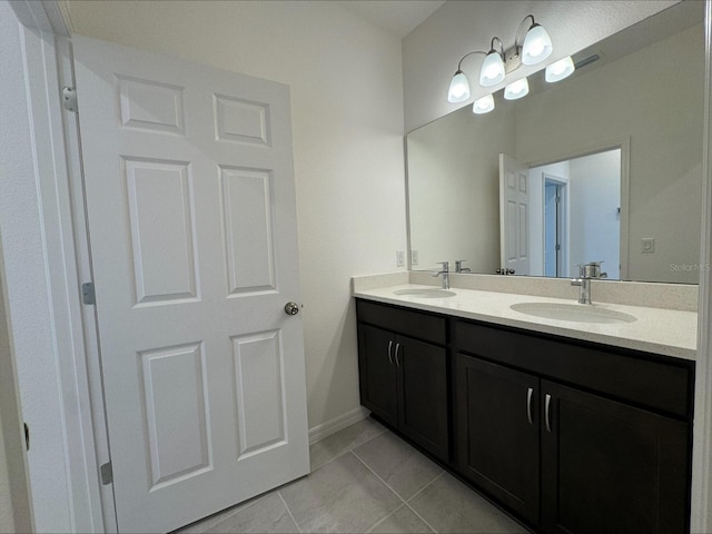 bathroom featuring double vanity, tile patterned flooring, a sink, and baseboards