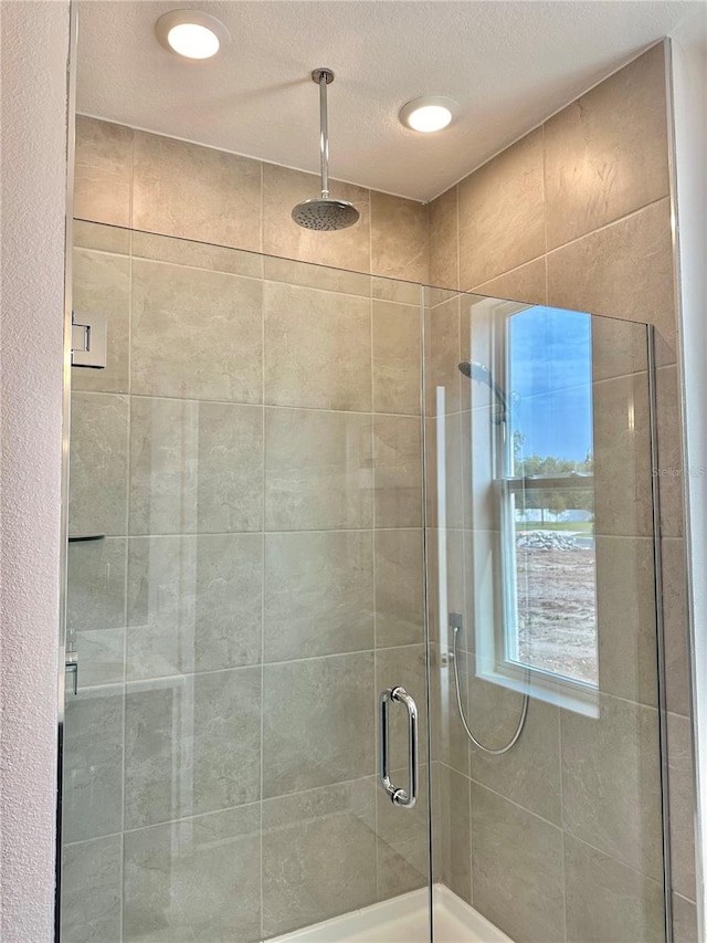 bathroom featuring a shower with door and a textured ceiling