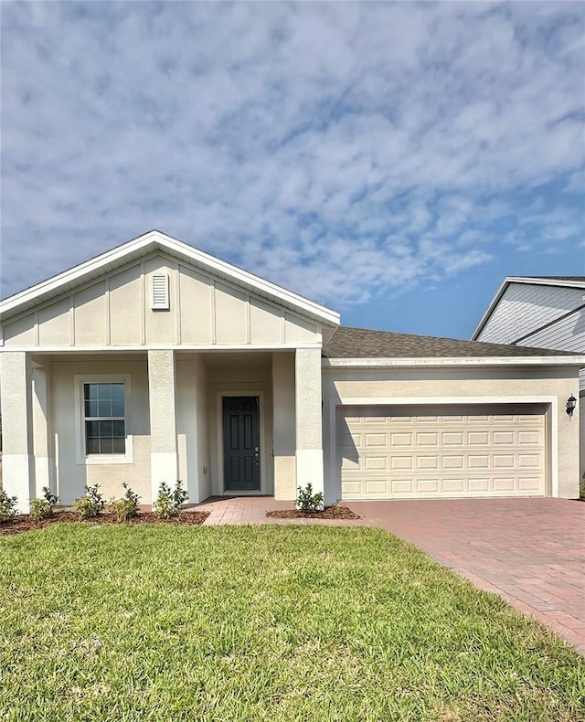 single story home featuring decorative driveway, stucco siding, an attached garage, and a front yard