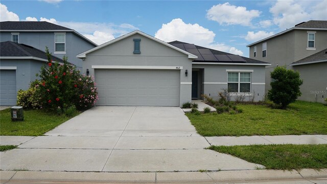 view of front of property featuring a garage, a front lawn, and solar panels