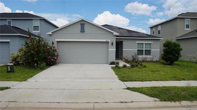 view of front of house with a garage, a front lawn, and solar panels