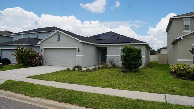 view of front of home featuring a garage, a front lawn, and solar panels