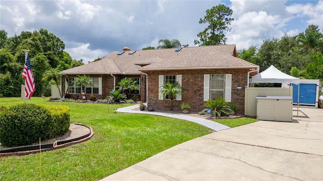 ranch-style home with brick siding, a front lawn, and roof with shingles