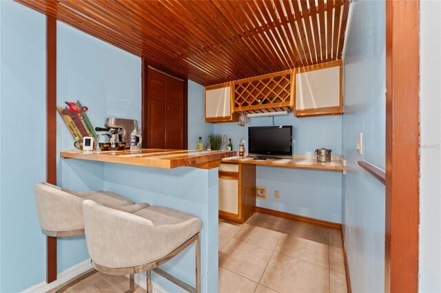 kitchen with a kitchen breakfast bar, wooden counters, light tile patterned floors, wood ceiling, and kitchen peninsula