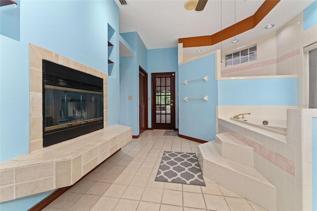 bathroom with a fireplace, a relaxing tiled tub, ceiling fan, and tile patterned floors