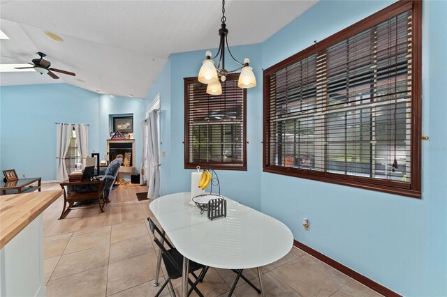 tiled dining space with vaulted ceiling and ceiling fan with notable chandelier